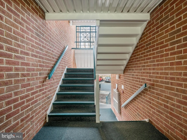 stairway featuring brick wall