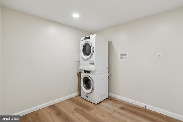 laundry room featuring recessed lighting, stacked washer and dryer, laundry area, baseboards, and light wood-type flooring