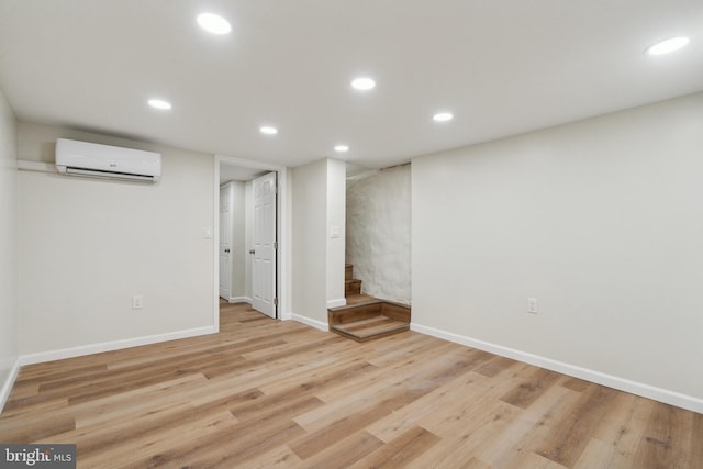 finished below grade area featuring an AC wall unit, recessed lighting, and light wood-style floors