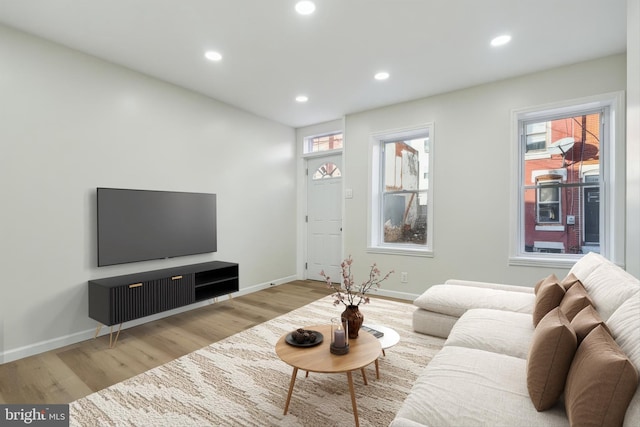 living area with baseboards, light wood-type flooring, and recessed lighting