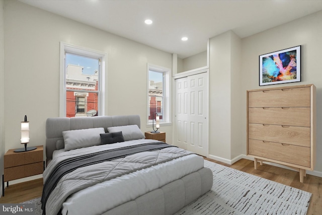 bedroom with recessed lighting, a closet, baseboards, and wood finished floors