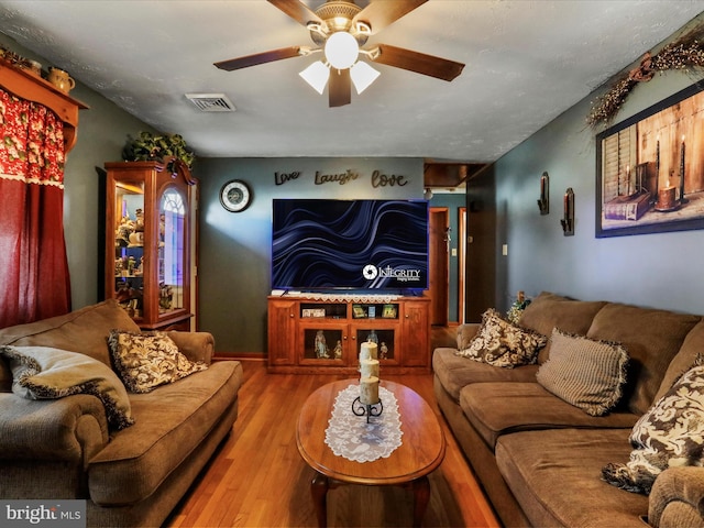 living room featuring ceiling fan, visible vents, and wood finished floors