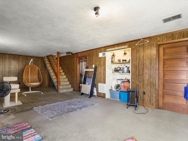 living area featuring wood walls, stairs, and visible vents