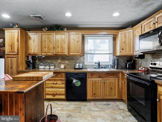 kitchen featuring butcher block countertops, a sink, visible vents, black appliances, and tasteful backsplash