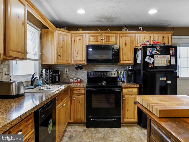 kitchen featuring tasteful backsplash, recessed lighting, a sink, butcher block countertops, and black appliances