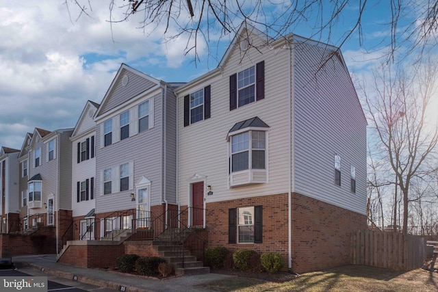 view of front of home featuring brick siding and fence