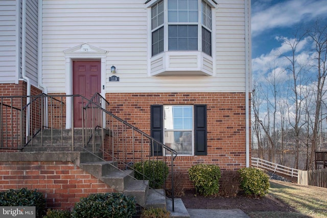 property entrance featuring fence and brick siding