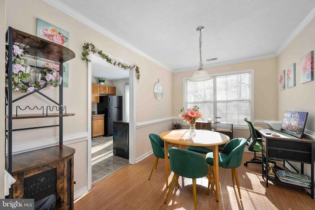 dining room with visible vents, crown molding, light wood-style flooring, and baseboards