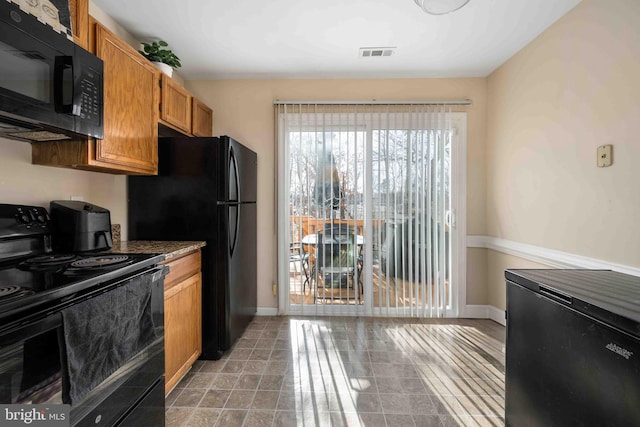 kitchen with brown cabinets, dark countertops, visible vents, black appliances, and baseboards