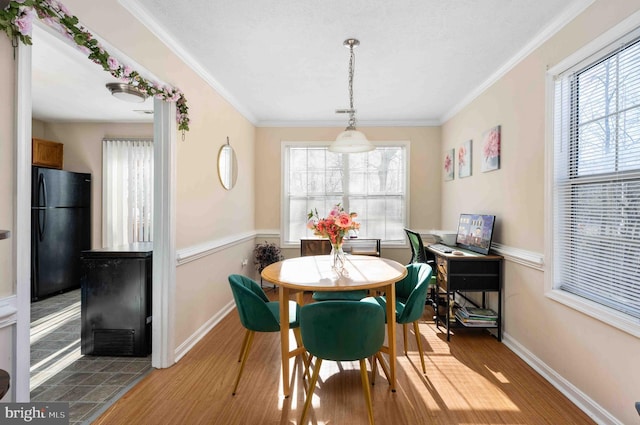 dining room featuring a healthy amount of sunlight, crown molding, and wood finished floors