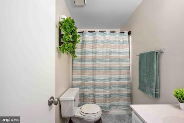 bathroom featuring curtained shower, vanity, and toilet