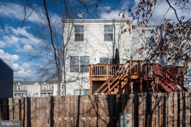 back of property featuring fence, a deck, and stairs