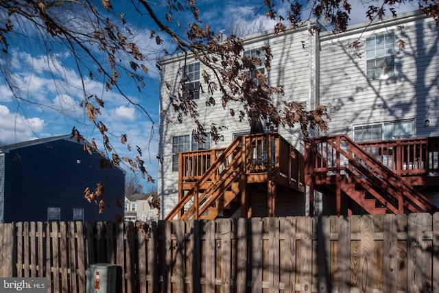 rear view of property featuring a deck, stairway, and fence private yard