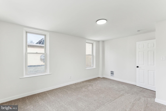 unfurnished room featuring light colored carpet, visible vents, and baseboards