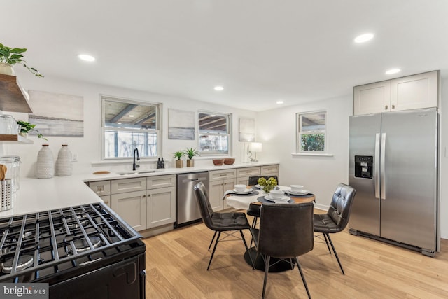 kitchen with stainless steel appliances, recessed lighting, light countertops, a sink, and light wood-type flooring