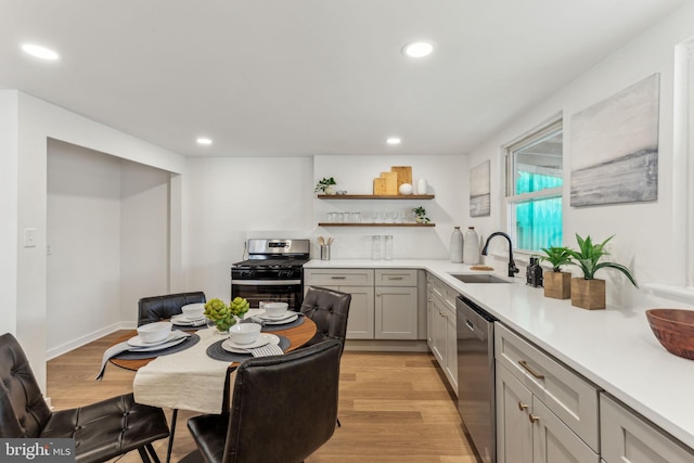 kitchen featuring recessed lighting, light countertops, appliances with stainless steel finishes, light wood-style floors, and a sink