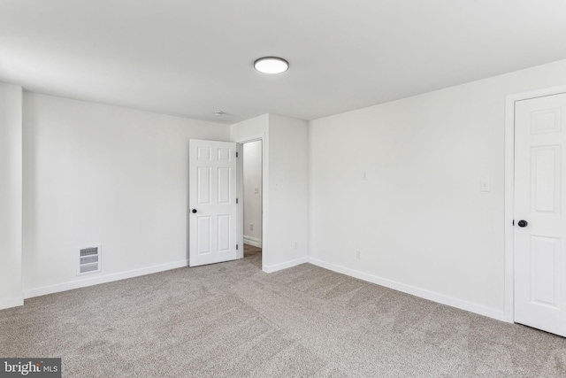 empty room featuring light carpet, visible vents, and baseboards