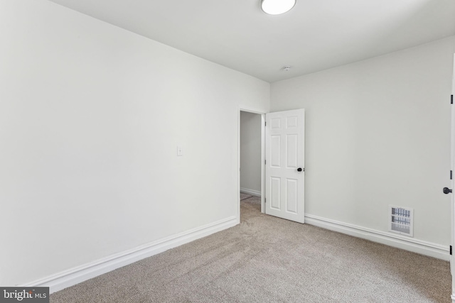 unfurnished room with visible vents, light carpet, and baseboards