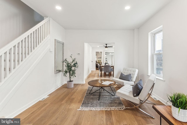 living area featuring recessed lighting, baseboards, light wood finished floors, and stairs