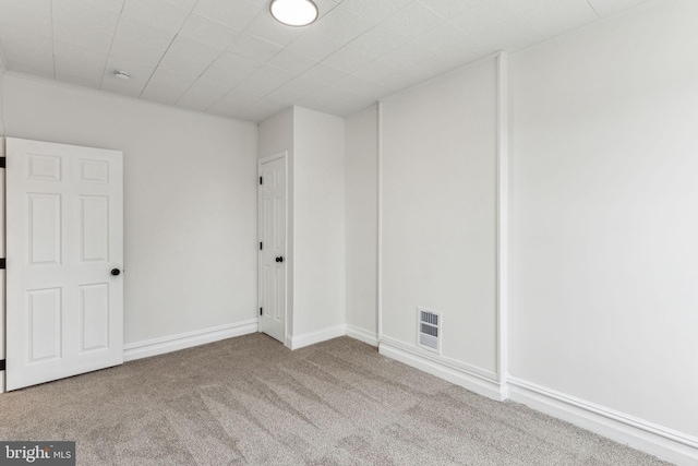 unfurnished room featuring carpet, visible vents, and baseboards