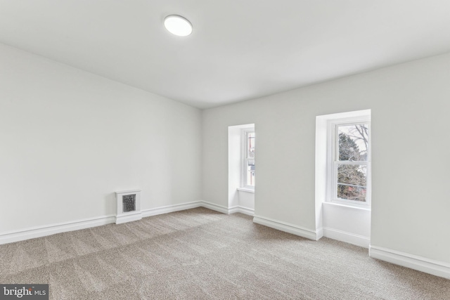 spare room featuring carpet floors, baseboards, and visible vents