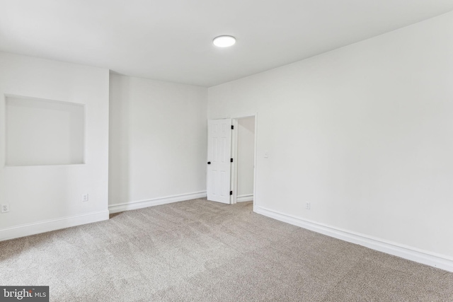 carpeted spare room featuring baseboards