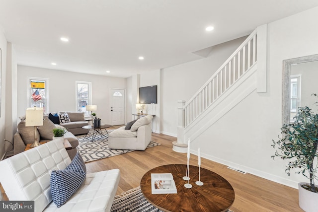 living room featuring baseboards, visible vents, wood finished floors, stairs, and recessed lighting