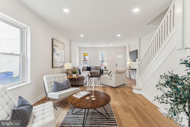 living room with light wood-type flooring, baseboards, recessed lighting, and stairs