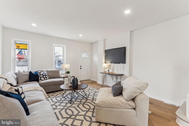 living area with light wood-type flooring, visible vents, baseboards, and recessed lighting