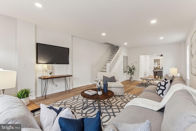 living room with light wood finished floors, stairs, baseboards, and recessed lighting