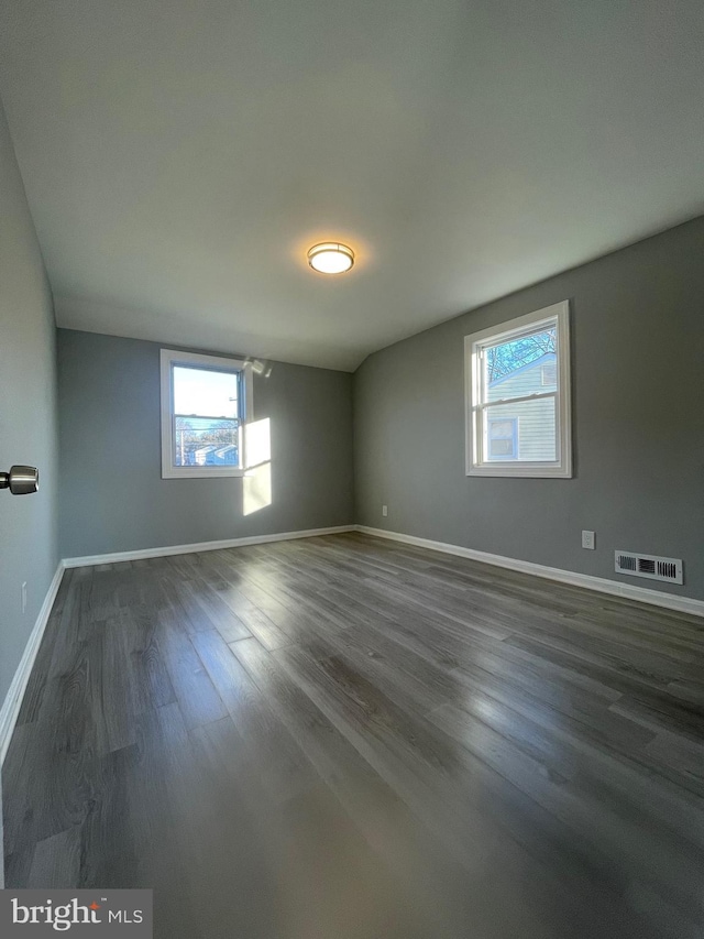 spare room featuring visible vents, dark wood finished floors, and baseboards