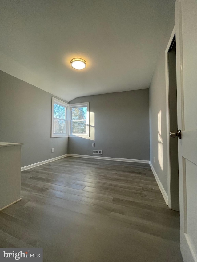 unfurnished room with dark wood-style flooring, visible vents, and baseboards