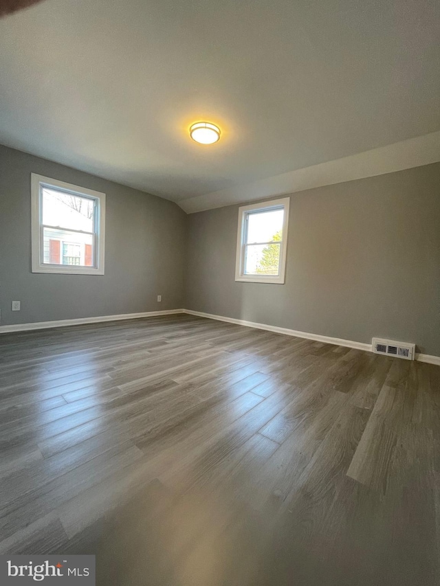 spare room featuring dark wood-type flooring, visible vents, and baseboards