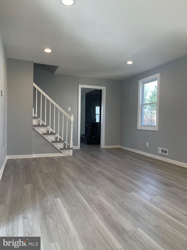 unfurnished living room featuring recessed lighting, visible vents, wood finished floors, baseboards, and stairs