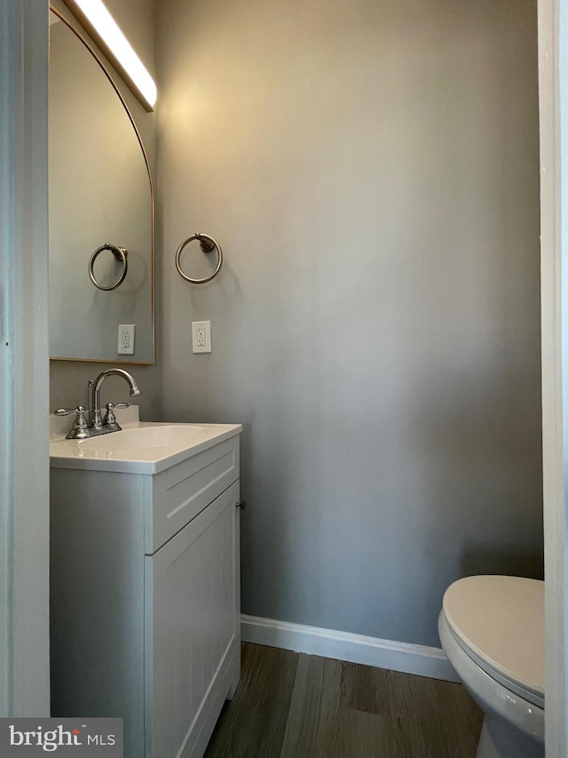 bathroom featuring toilet, vanity, baseboards, and wood finished floors