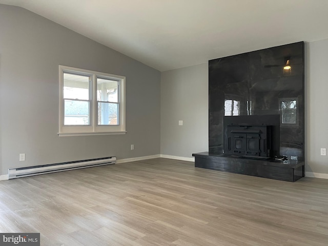 unfurnished living room featuring a baseboard heating unit, lofted ceiling, light wood-type flooring, and a wood stove