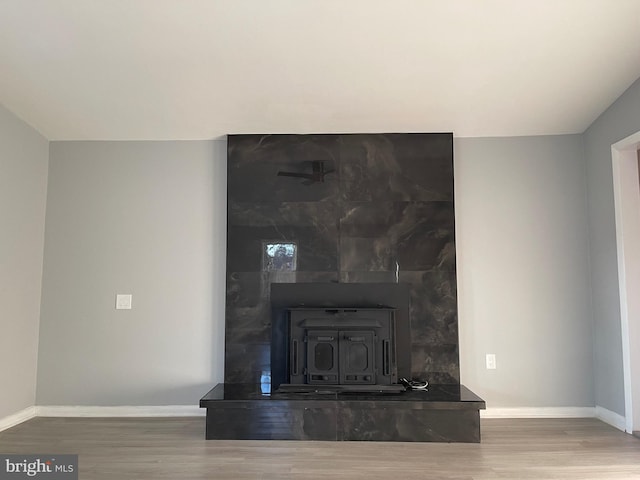 interior details with wood finished floors, a wood stove, and baseboards