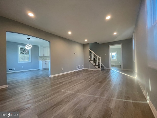 unfurnished living room featuring stairway, wood finished floors, visible vents, and recessed lighting