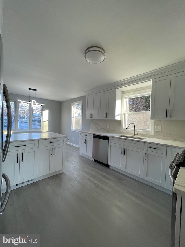 kitchen with stainless steel appliances, light countertops, a sink, and white cabinetry