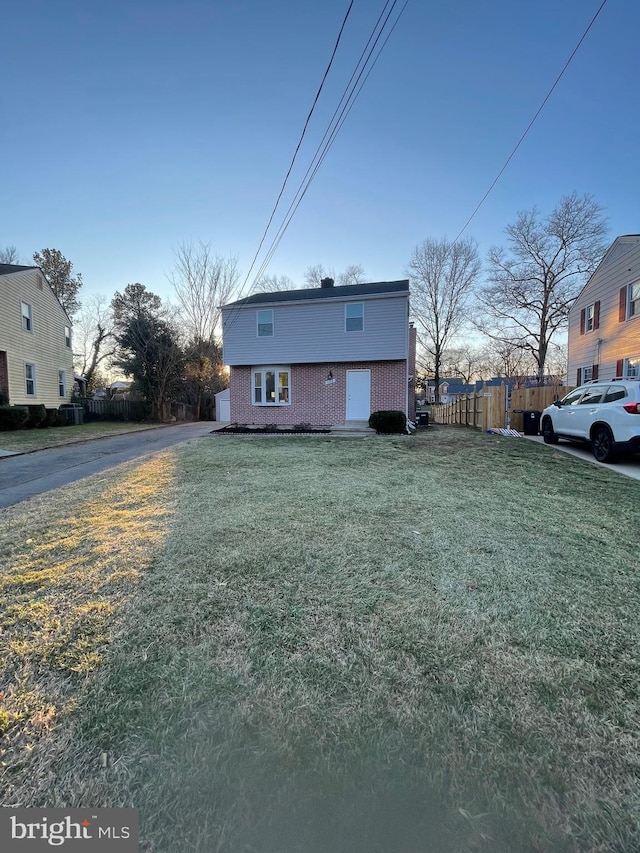 view of front of house featuring fence, a front lawn, and brick siding