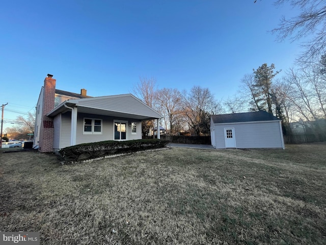 view of front of property with an outbuilding, a chimney, and a front yard