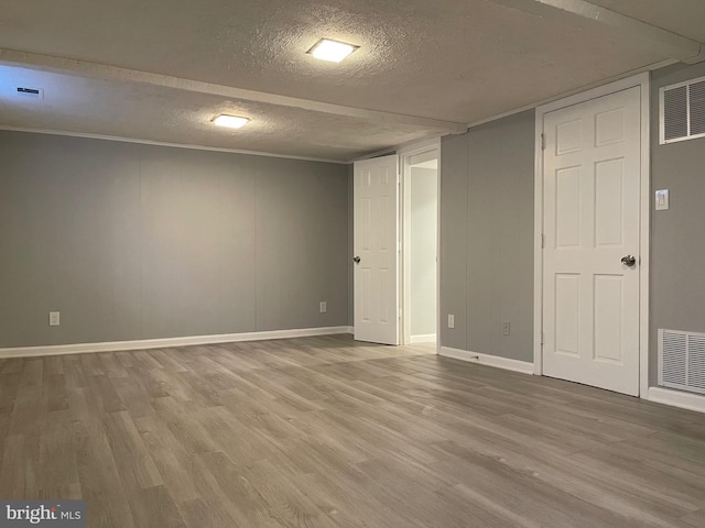 below grade area featuring visible vents, a textured ceiling, and wood finished floors