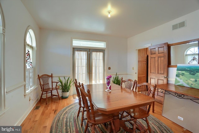 dining room with light wood-style floors, visible vents, and french doors