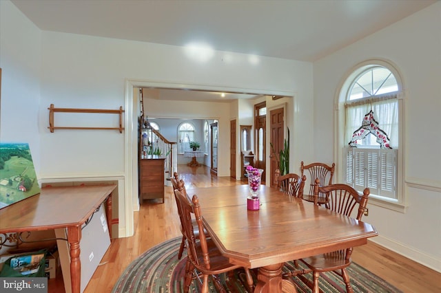 dining space featuring stairs, baseboards, and light wood-style floors