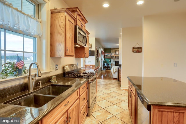 kitchen with light tile patterned floors, brown cabinetry, stainless steel appliances, a sink, and recessed lighting