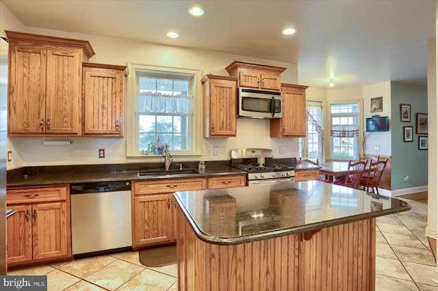 kitchen with light tile patterned floors, appliances with stainless steel finishes, brown cabinets, a sink, and recessed lighting