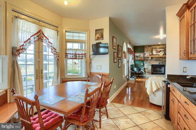 dining room featuring french doors, light tile patterned flooring, a fireplace, and a wealth of natural light