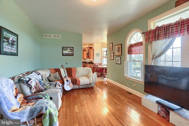 living area featuring baseboards, visible vents, and light wood-style floors