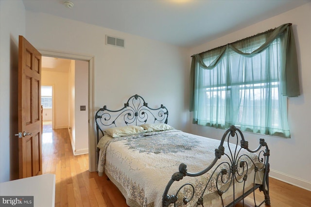 bedroom with wood finished floors, visible vents, and baseboards