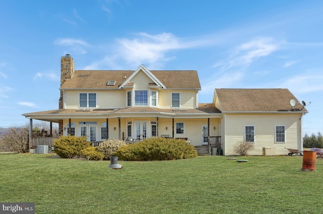 view of front facade with a chimney, a porch, central AC, and a front yard